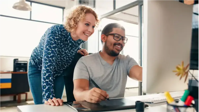 two colleagues smiling at computer
