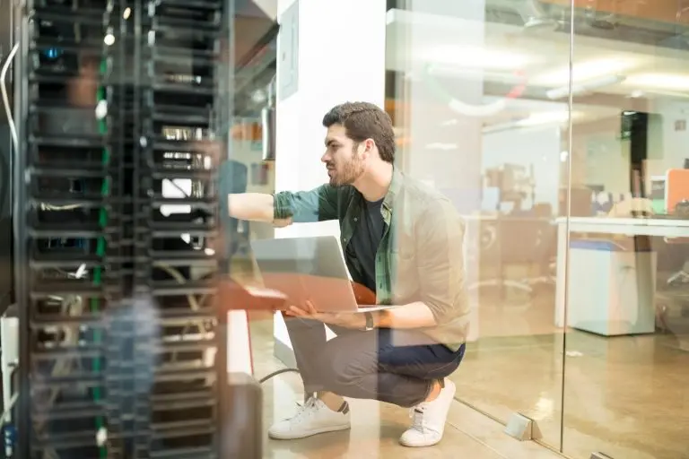 man troubleshooting server with laptop