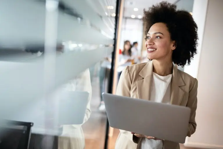Woman with laptop smiling indoors