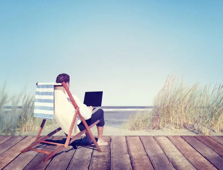 man on beach with laptop