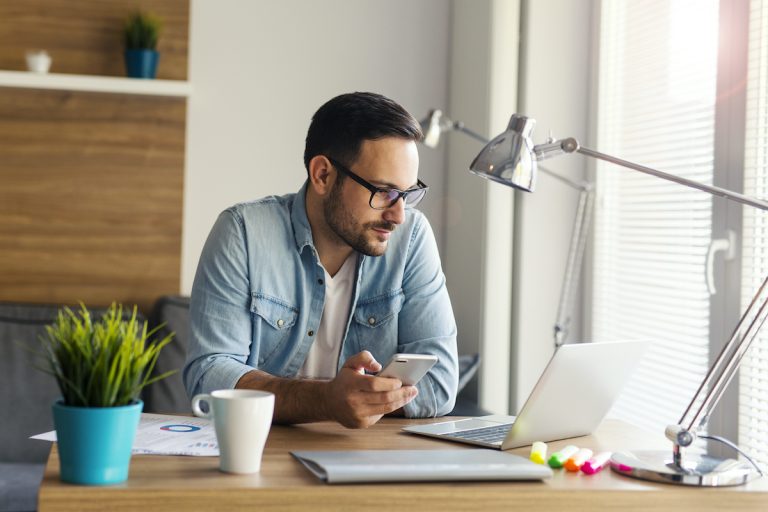 man using phone and laptop